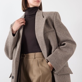 Model wearing Source Unknown Reyna Double-Breasted Coat in beige wool, styled with a dark turtleneck and tailored trousers.