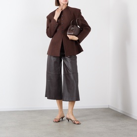 Model wearing Source Unknown Banton Double-Breasted Brown Jacket, collarless with structured shoulders, styled with dark leather culottes and heeled