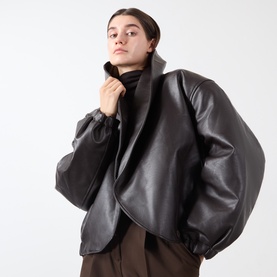 Model wearing Source Unknown Eleni Faux Leather Jacket in brown with shawl collar and dropped shoulders, styled with brown trousers
