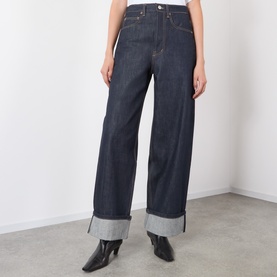 Model wearing Source Unknown Piero Wide Leg Jeans in blue, high-rise with wide-leg silhouette, turn-up hems and dark wash finish, styled with black