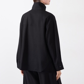 Model wearing black high-neck long-sleeve shirt, rear view, paired with wide-leg black trousers