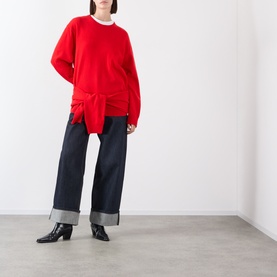 Model wearing Source Unknown Tio Shawl Sweater in red with layered shawl hem, styled with wide-leg cuffed jeans and black heeled boots.