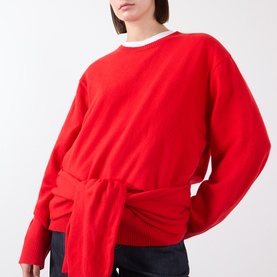 Model wearing Source Unknown Tio Shawl Sweater in red, featuring draped shawl wrap detail at waist, dropped shoulders, styled with white tee and jeans