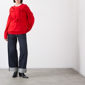 Model wearing Source Unknown Tio Shawl Sweater in red with layered shawl detail, styled with dark wide-leg jeans and black patent boots