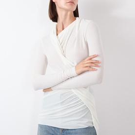 Model wearing Source Unknown Folgore Draped Top in ivory, featuring asymmetric wrap neckline, ruched detailing, and long sleeves