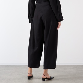 Model wearing Source Unknown Bimba Pintuck Trousers in black, wide-leg cropped cut with pintuck detail, styled with black mules and dark top.