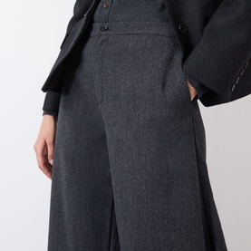 Model wearing Source Unknown Ebbe Balloon Trousers in charcoal, mid-rise balloon-leg silhouette with button fastening, styled with a dark blazer.