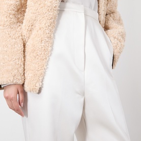 Model wearing Source Unknown Ocelia Satin Trousers in white, straight-leg cropped cut, styled with a beige textured shearling jacket