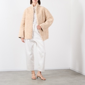 Model wearing Source Unknown Ocelia Satin Trousers in white, styled with a cream shearling jacket and tan strappy sandals.