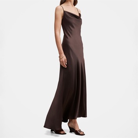 Model wearing dark brown satin slip maxi dress with cowl neck and thin straps, styled with black strappy sandals