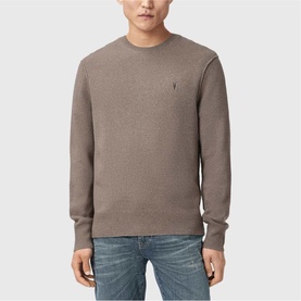 Model wearing a taupe marl crew neck knit sweater with small logo embroidery, styled with blue jeans.