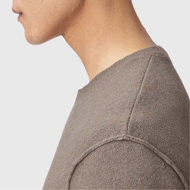Close-up of a taupe textured fleece sweatshirt showing shoulder seam detail and soft fabric finish