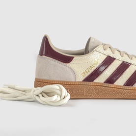 Adidas trainer in off-white and shadow red with three-stripe detail, gum sole, and cream laces
