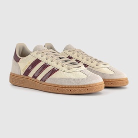Adidas trainers in off-white with shadow red suede three-stripe detailing, low-top lace-up silhouette, and gum rubber sole.