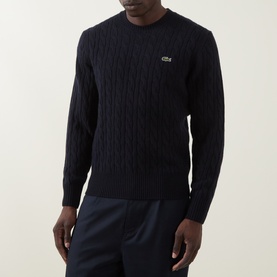 Model wearing Lacoste navy blue wool cable-knit crew neck jumper with crocodile logo, styled with navy trousers