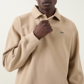 Model wearing Lacoste polo sweat in Viennese beige, featuring a spread collar, zip placket, and embroidered crocodile logo