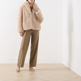 Model wearing Marella sand faux shearling coat, styled with khaki wide-leg trousers and nude heels.