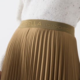 Model wearing Marella oil green pleated skirt with branded elasticated waistband, styled with white textured top.