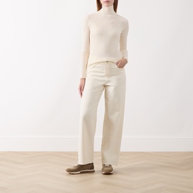 Model wearing Marella white fine-knit turtleneck top, styled with cream wide-leg jeans and taupe loafers.
