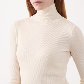 Model wearing Marella white ribbed turtleneck top in lyocell-wool blend with long sleeves and fitted silhouette.