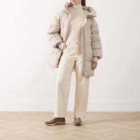 Model wearing Marella white top styled with a beige puffer coat, cream wide-leg trousers and tan loafers.