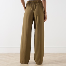 Model wearing Marella oil green wide-leg wool trousers, shown from behind with elasticated waistband detail.