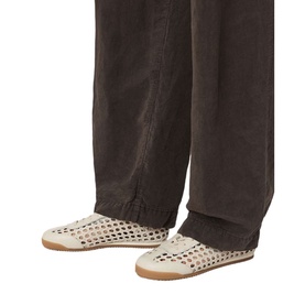 Model wearing All Saints parchment white woven cut-out flat shoes with tan rubber sole, styled with dark brown wide-leg trousers.
