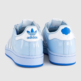 Adidas Superstar trainers in light blue patent leather with white stripes, blue cloud heel tab, and bright blue sole