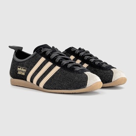 Adidas Japan trainers in core black and sand strata, textured upper with cream three stripes, gold branding, and gum sole