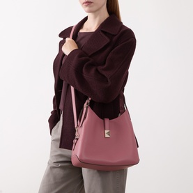 Model carrying Kate Spade Deco Medium Tote Bag in Pomegranate with gold-tone hardware and adjustable strap, styled with dark burgundy coat