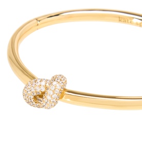 Kate Spade gold-tone bangle with pav&eacute; cubic zirconia knot detail, polished finish, clear and gold colourway