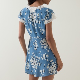 Model wearing Rixo London Bouquet Blue floral mini dress, rear view, with lace trim short sleeves and a relaxed fit skirt.