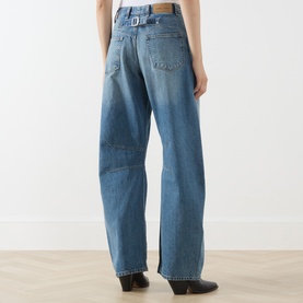 Model wearing Samsoe & Samsoe Sephia Blue wide-leg jeans, rear view, styled with black ankle boots. Belt loops and back patch pocket visible.