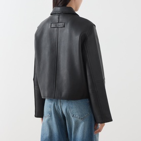 Model wearing Samsoe & Samsoe black leather jacket, rear view, styled with light blue jeans