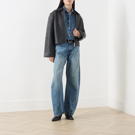 Model wearing Samsoe & Samsoe black leather jacket, styled with blue denim shirt, light-wash wide-leg jeans and black leather shoes.