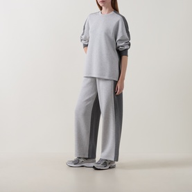 Model wearing Spanx Sweat Bottoms in grey with contrast dark grey side panels, paired with matching grey sweatshirt and grey trainers.