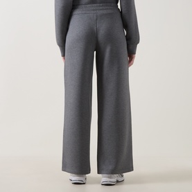 Model wearing Spanx Sweat Bottoms in grey heather, wide-leg style, styled with matching grey sweatshirt and white trainers.