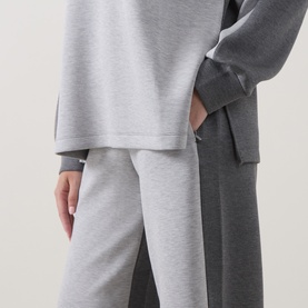 Model wearing Spanx Sweat Bottoms in light grey marl, styled with a matching grey oversized sweatshirt. Relaxed wide-leg fit.