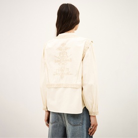 Model wearing Bash cream jacket with embroidered back detail and gathered sleeves, styled with blue jeans