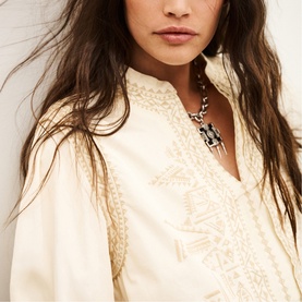 Model wearing Bash cream embroidered blouse with mandarin collar, styled with a silver and black statement pendant necklace.