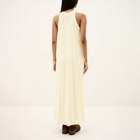 Model wearing Bash cream sleeveless pleated maxi dress, back view, styled with brown flat shoes.