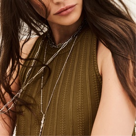 Model wearing Bash brown ribbed sleeveless top, styled with layered silver chain necklaces