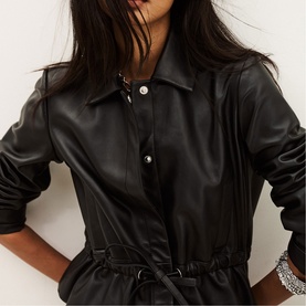 Model wearing Bash black faux leather belted shirt dress with button front and collar, styled with silver bracelets