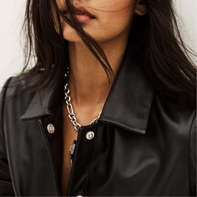 Model wearing Bash black leather jacket with silver button detail, styled with a chunky silver chain-link necklace
