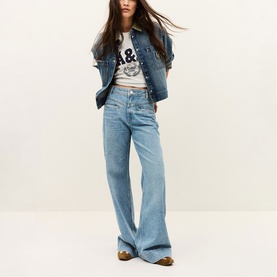 Model wearing Bash blue wide-leg jeans with denim jacket, graphic tee and metallic loafers