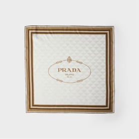 Prada Accessories neutral silk scarf with gold and brown striped border and embossed logo centre, laid flat.