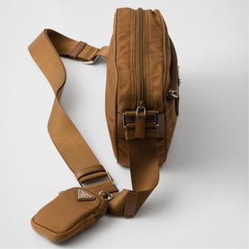 Tan nylon belt bag with silver-tone hardware, zip compartments, and adjustable crossbody strap with triangular logo plaque