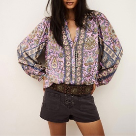 Model wearing Bash purple paisley print boho blouse with balloon sleeves, styled with dark grey denim shorts and brown belt
