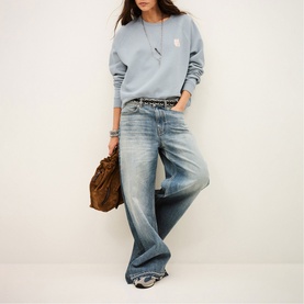 Model wearing Bash blue wide-leg jeans, styled with a light blue sweatshirt and brown bag