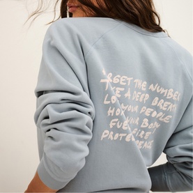 Model wearing Bash blue sweatshirt, back view with white handwritten-style slogan text print.